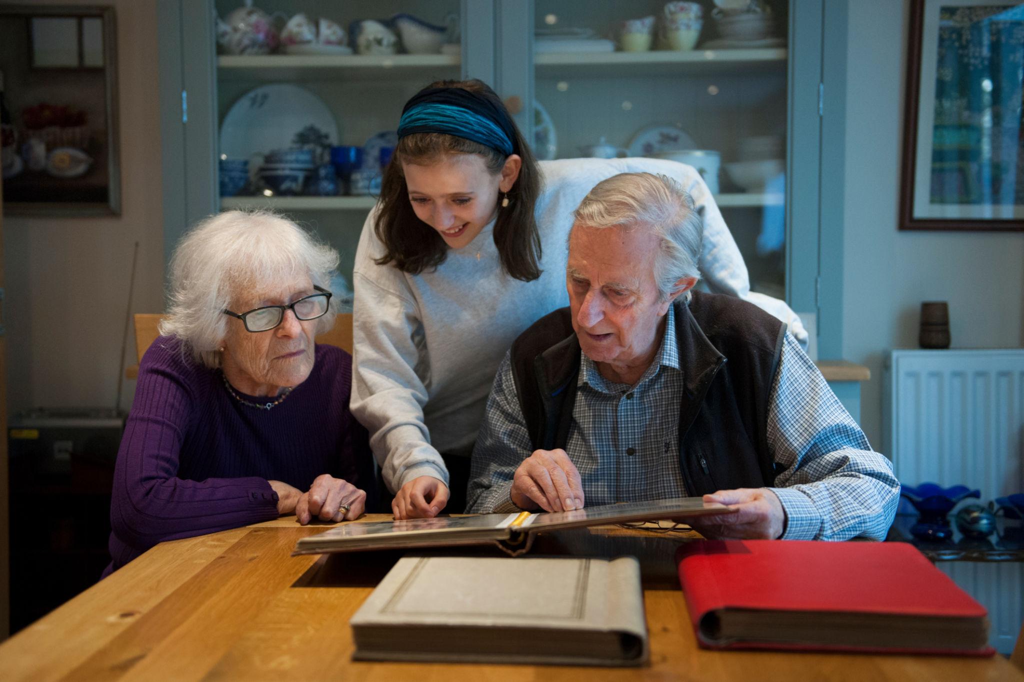 Three generations looking through a family photo album together